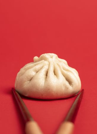 Bao dumpling close-up and chopsticks isolated on a red background