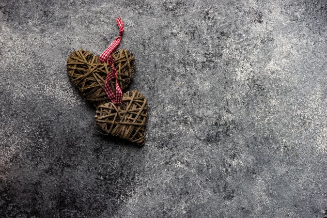 Thatched heart ornaments with checkered red ribbon on grey counter