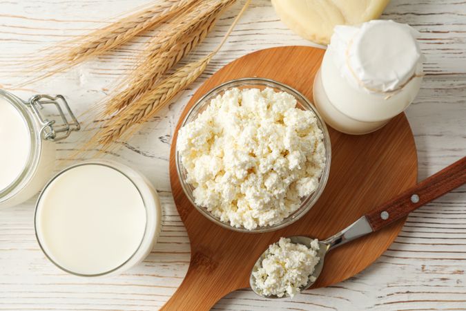 Spikelets of wheat, dairy products and board on wood background, top view