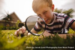 Boy looking through magnifying glass on a sunny day 5z8qob