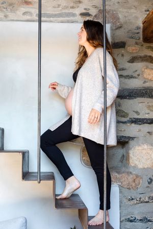 Pregnant woman ascending stairs in rustic home
