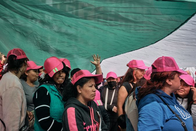 Mexico City, Mexico - February 26th, 2022: Group of people in pink hats in front of Mexican flag