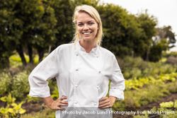 Self-sustainable female chef smiling at the camera cheerfully in an agricultural field 0W6djb