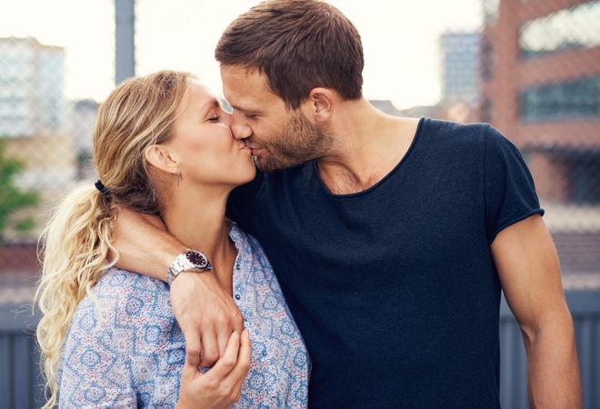 Close up of couple kissing with man’s arm on woman’s shoulder