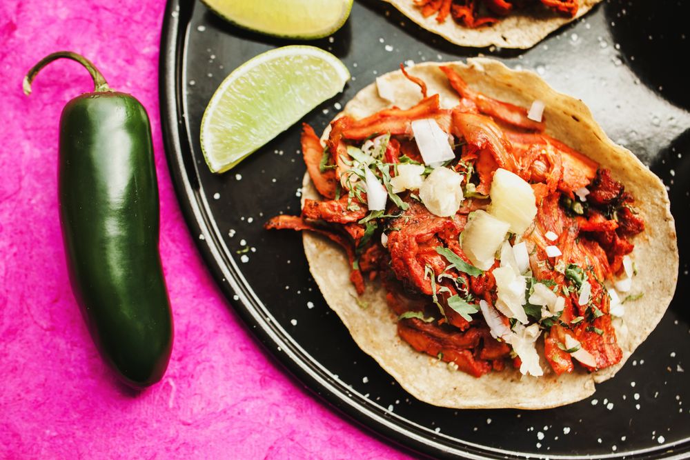 Pepper and lime near tacos al pastor and sauces