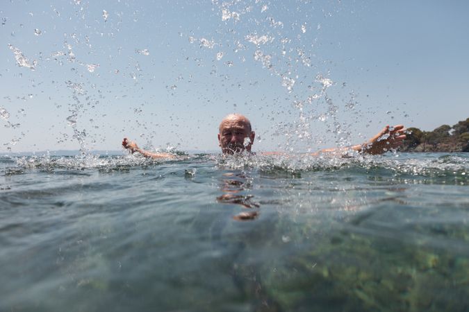 Active man swimming and splashing in water