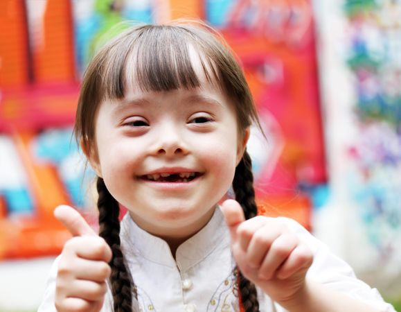 Portrait of happy girl with Down syndrome doing the thumbs up sign