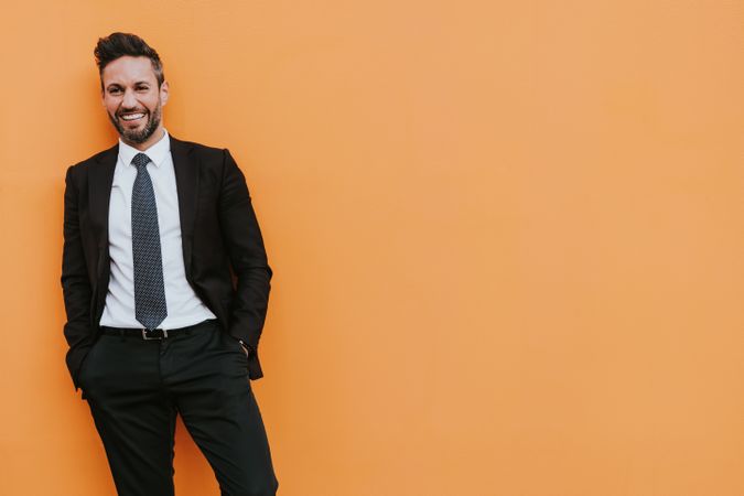 Adult stylish man in costume near orange wall