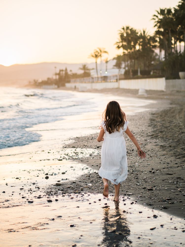 Adorable girl walking on seaside at sunset