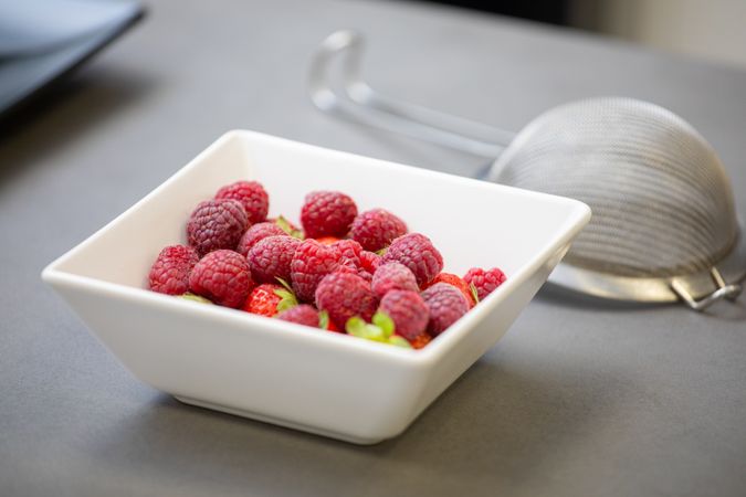 Juicy ripe raspberries in square bowl on table