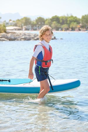 Boy walking in sea and dragging paddleboard