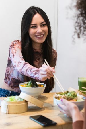 Delighted friendly multiethnic women eating in restaurant