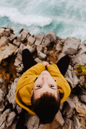 Woman in yellow hoodie on stony shore