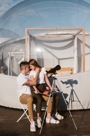 Young romantic couple using astronomical telescope