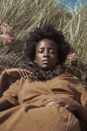 Woman in brown dress laying on green grass field