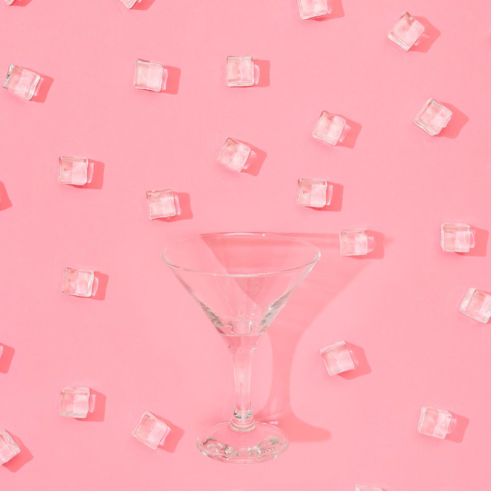 Martini glass with ice cubes pattern on pastel pink background