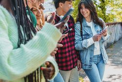 Multi-ethnic group of students texting on their phones on campus