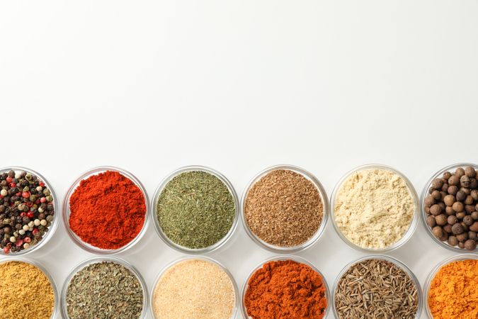 Two rows of colorful spices on plain background with copy space
