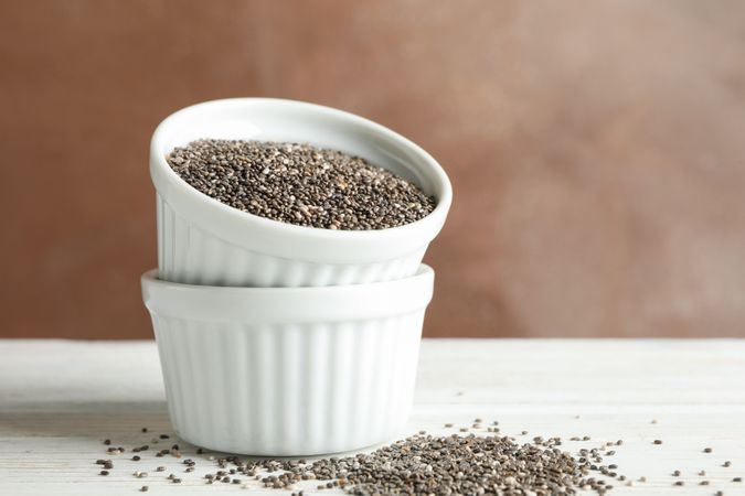 Ceramic sauce boats with chia on wooden background, copy space
