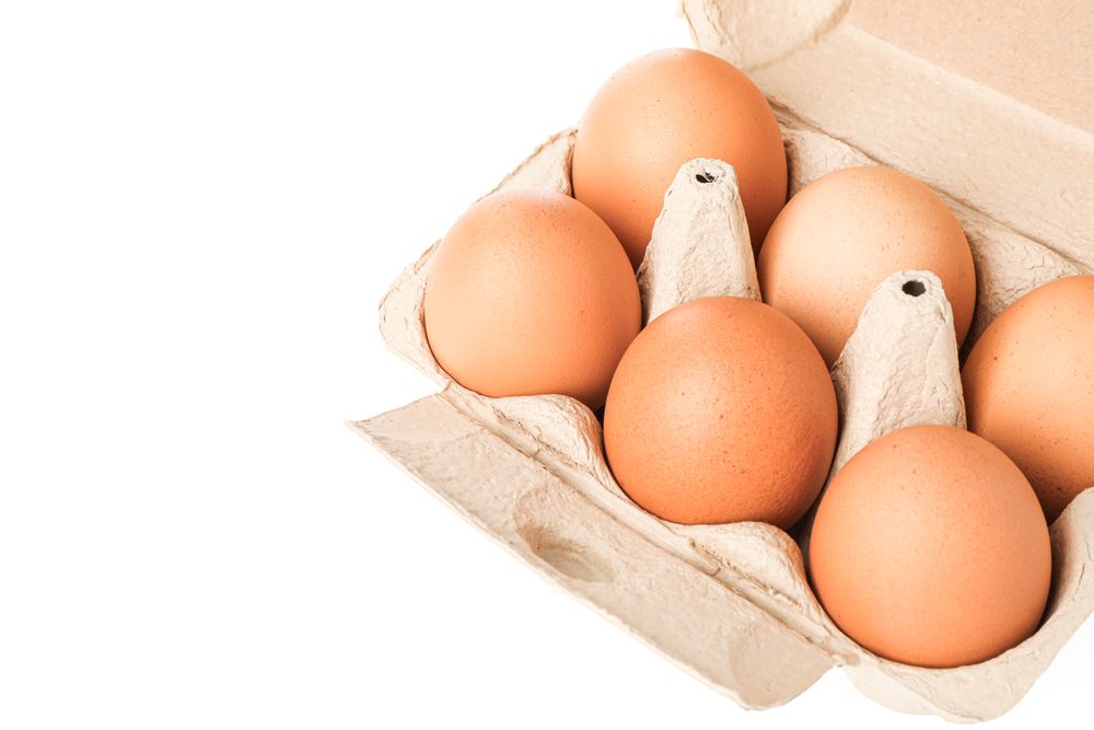 Brown chicken eggs in carton box isolated on light background