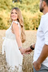 Smiling anticipating couple in white dress standing in field