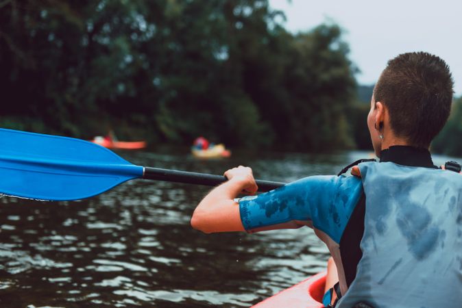 Female kayaking with paddle in raised hands