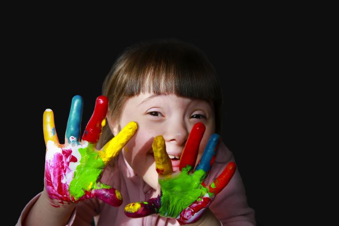 Happy girl showing her hands to the camera with paint on them