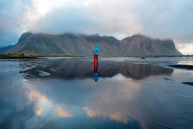 Back view of person standing in sparse outdoor near Vestrahorn mountain in Stokksnes peninsula, Hofn, Iceland