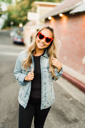 Smiling woman in denim jacket wearing sunglasses