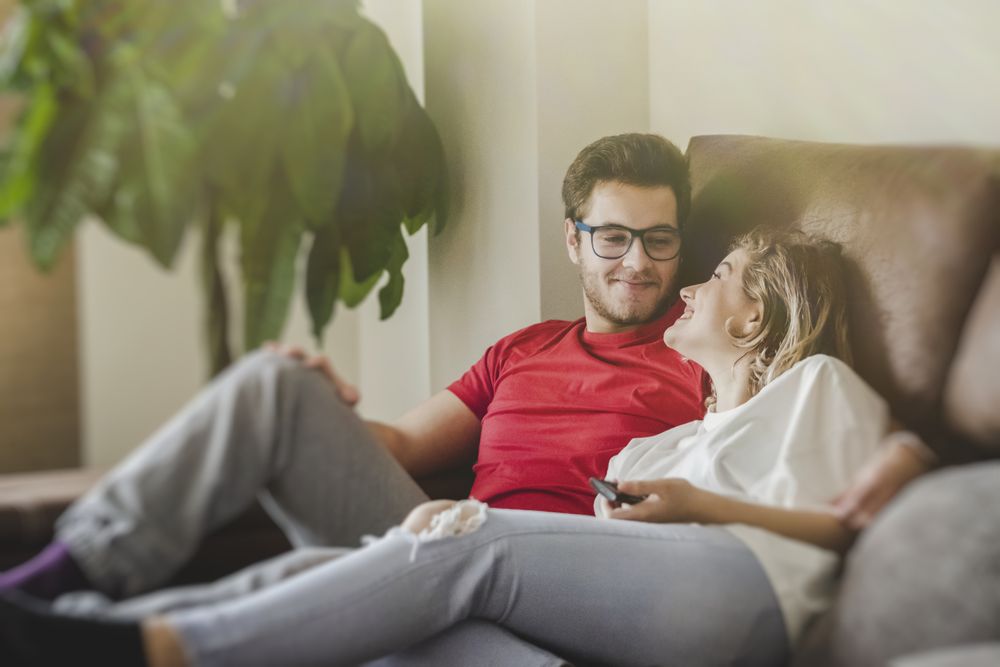 Happy couple watching TV on sofa