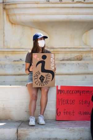 Los Angeles, CA, USA — June 16th, 2020: woman sitting on fountain at protest rally