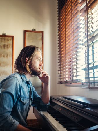 Thoughtful male playing synthesizer at home