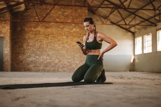 Fitness woman resting after workout and using mobile phone
