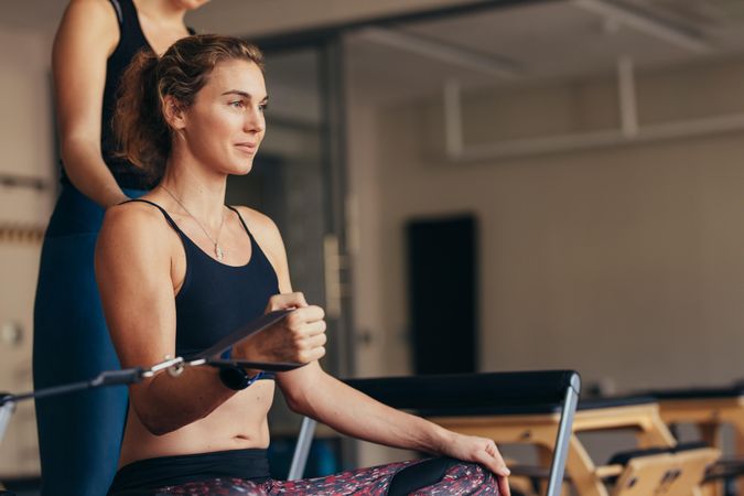 Woman exercising her arm muscles on pilates rack