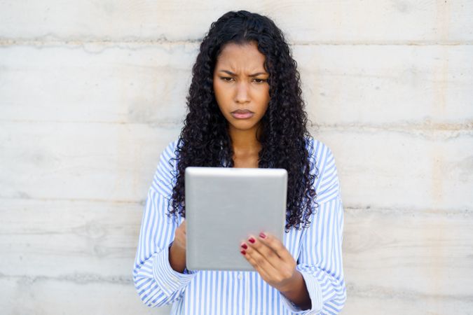 A Young Woman Deeply Engrossed in a Tablet Device, Exhibiting a Serious Expression