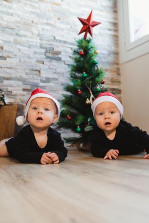 Happy babies near Christmas tree and gifts