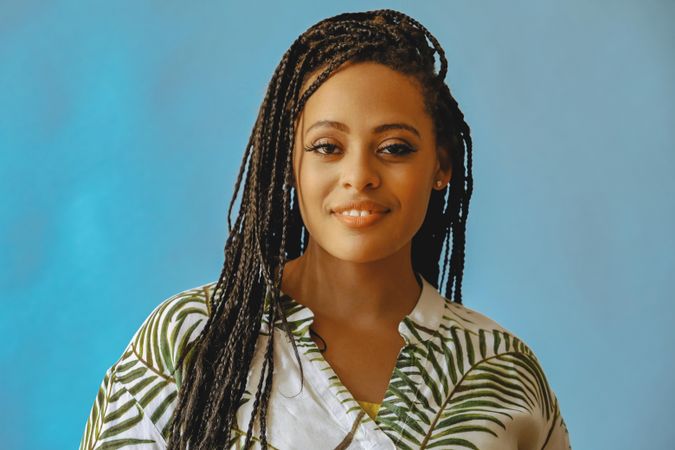 Portrait of confident female with long braided hair in printed leaf shirt