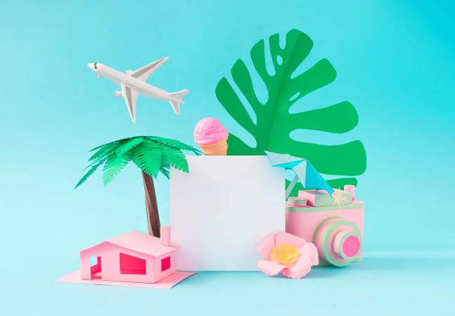 Pink paper house, ice cream, camera, palm tree, monstera leaf and airplane on blue background