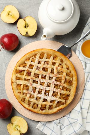 Composition with apple pie and ingredients on gray background, top view