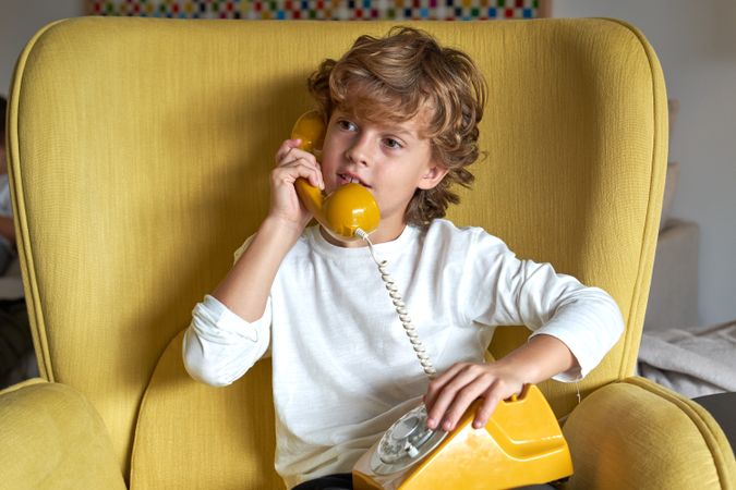 Interested boy speaking on old fashioned wired phone