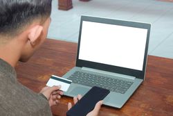 Back of male paying for something in front of laptop