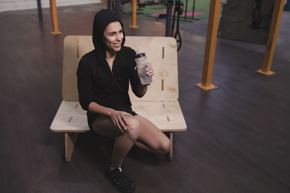 Smiling woman with bottle of water in gym
