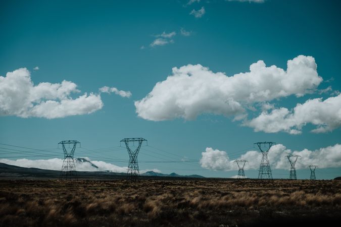 Power lines on autumn field under bright blue sky