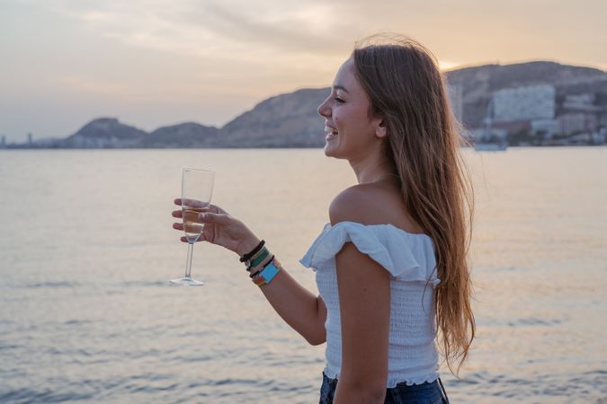 Young woman enjoying wine near sea