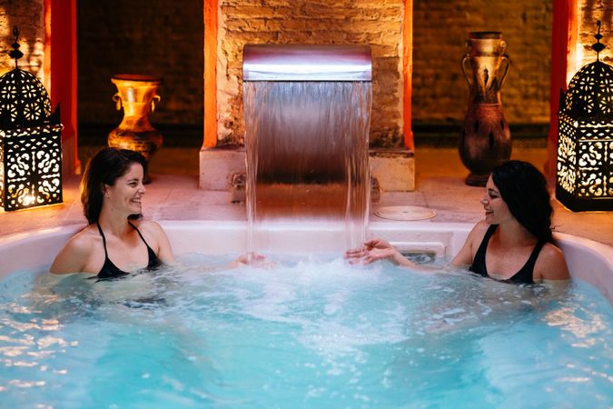 Female friends sitting under pouring water in spa