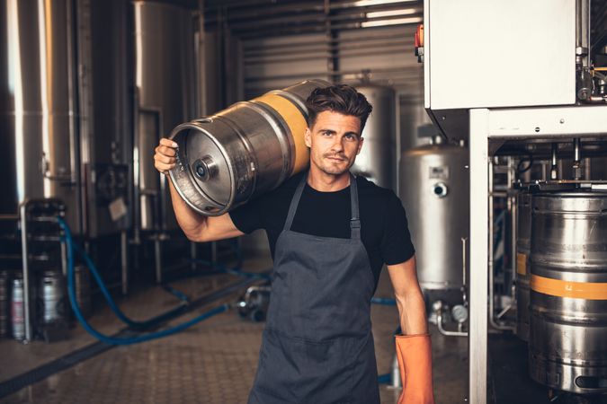 Craft brewer working in keg storage room with metal tanks in background