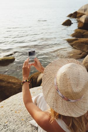 Contemporary woman with phone chilling on seashore