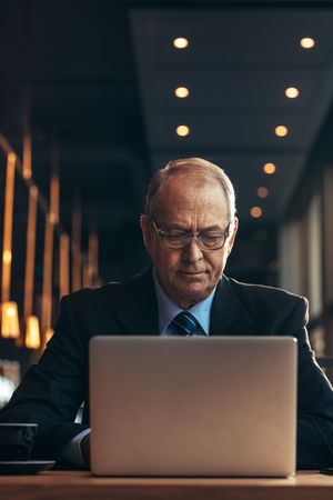 Mature businessman working on laptop while sitting at cafe