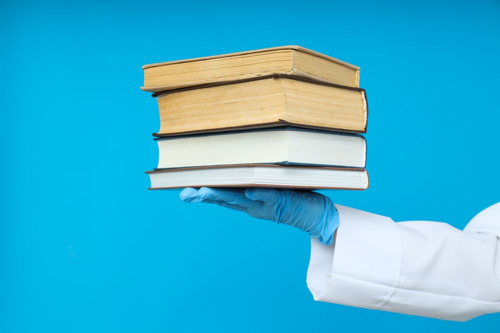 Doctors hand in glove holds books on blue background
