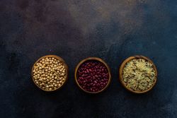 Top view of dry beans and rice in bowls on grey counter with copy space